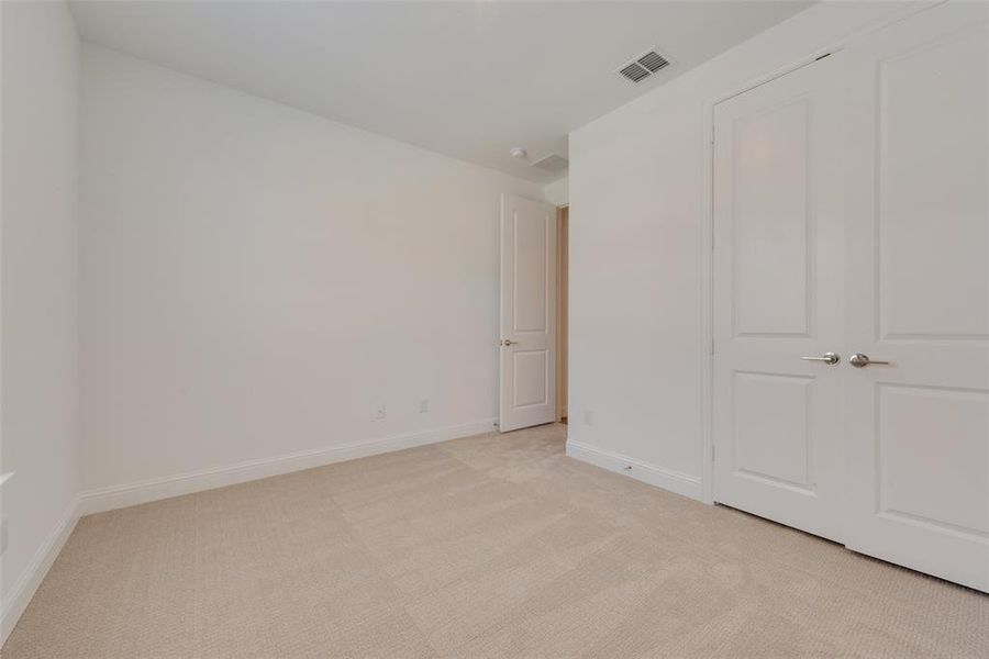 Unfurnished bedroom featuring light carpet and a closet