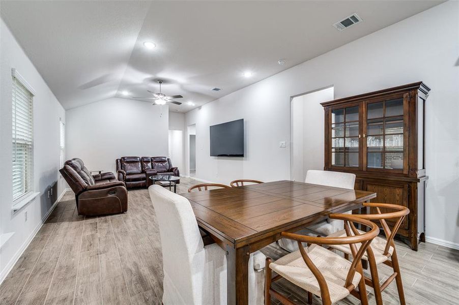 Dining area with ceiling fan, light hardwood / wood-style floors, and vaulted ceiling