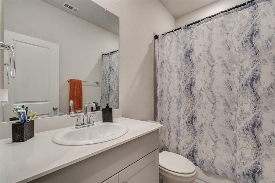 Bathroom featuring a shower with shower curtain, vanity, and toilet