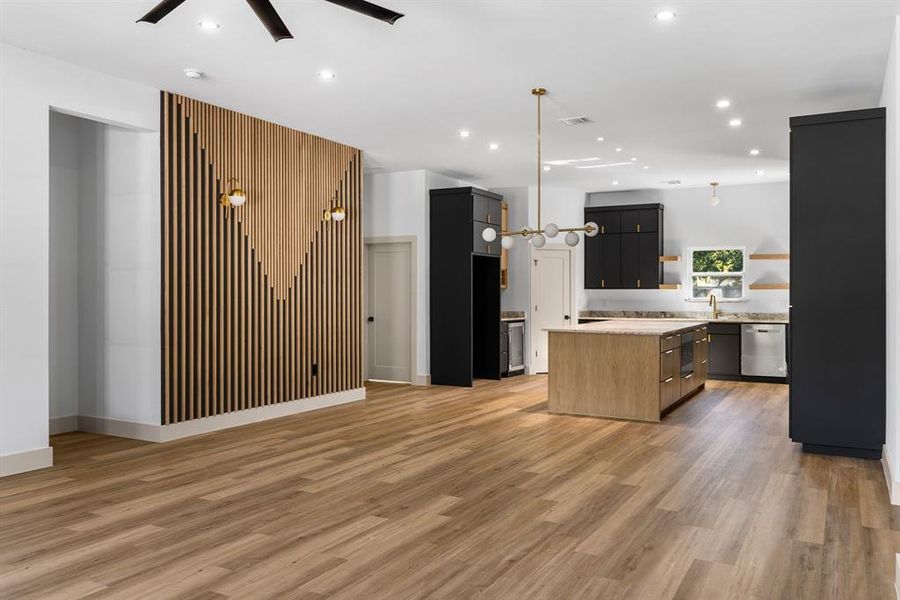 Kitchen with light wood-type flooring, stainless steel appliances, ceiling fan, decorative light fixtures, and a center island