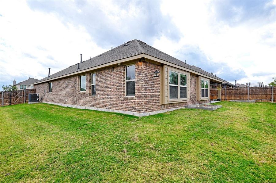 Rear view of property with a yard and central AC