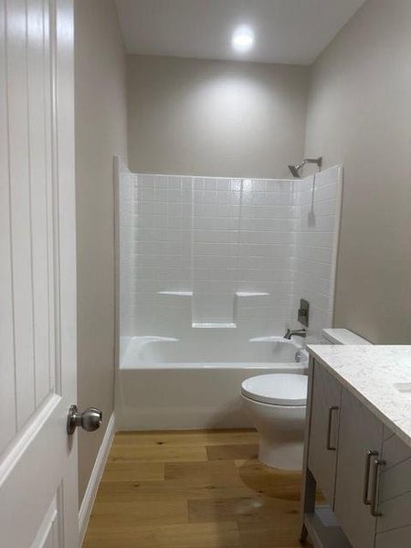 Full bathroom featuring washtub / shower combination, vanity, toilet, and hardwood / wood-style floors