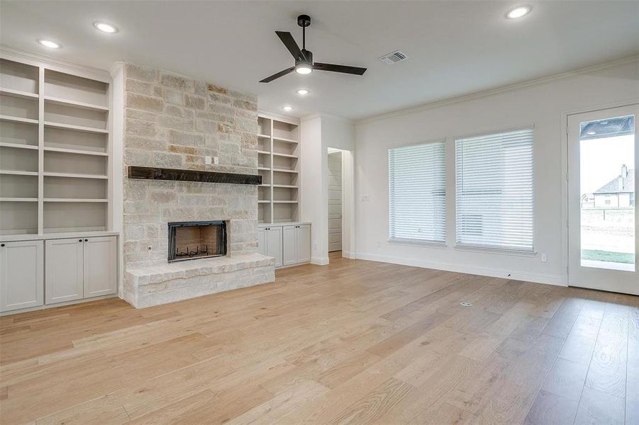 Unfurnished living room with light hardwood / wood-style floors, ornamental molding, a fireplace, and ceiling fan