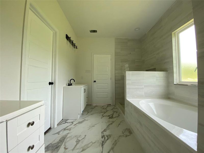 Bathroom featuring vanity, tiled tub, tile patterned flooring, and a wealth of natural light