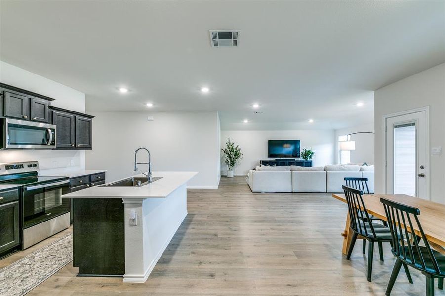 Kitchen featuring light hardwood / wood-style floors, stainless steel appliances, a center island with sink, and sink