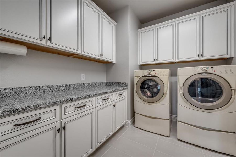 Laundry Room with light tile patterned floors, cabinets and granite countertop