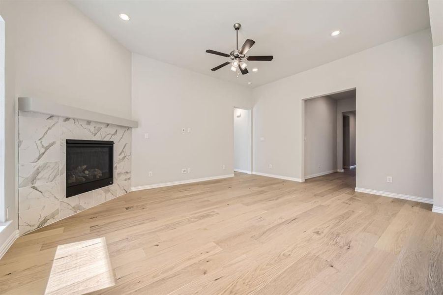 Unfurnished living room with a high end fireplace, light wood-type flooring, and ceiling fan