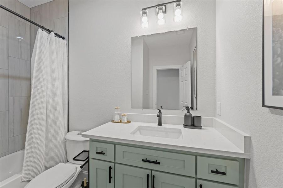 Full bathroom featuring toilet, vanity, and shower / bathtub combination with curtain