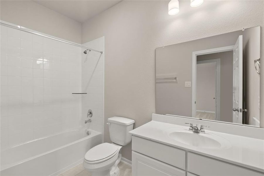 The secondary bath features tile flooring, white cabinetry and light countertops and a shower/tub combo. Perfect for accommodating any visiting family and friends.