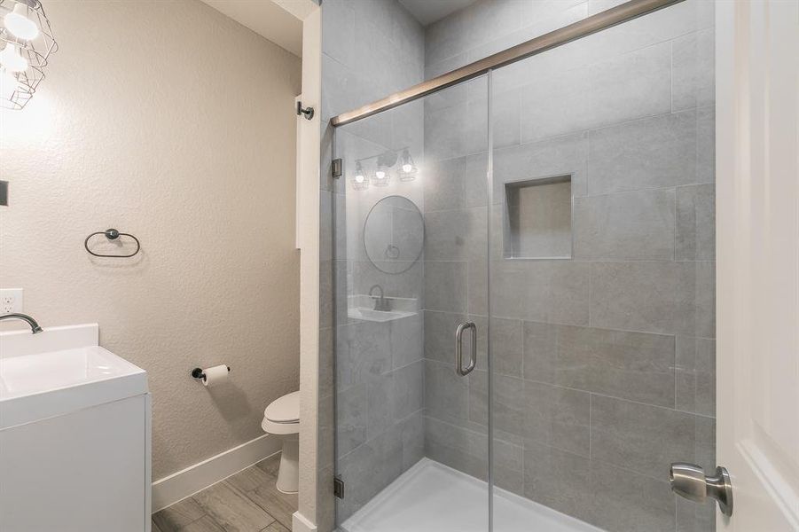Bathroom featuring a shower with shower door, wood-type flooring, toilet, and vanity
