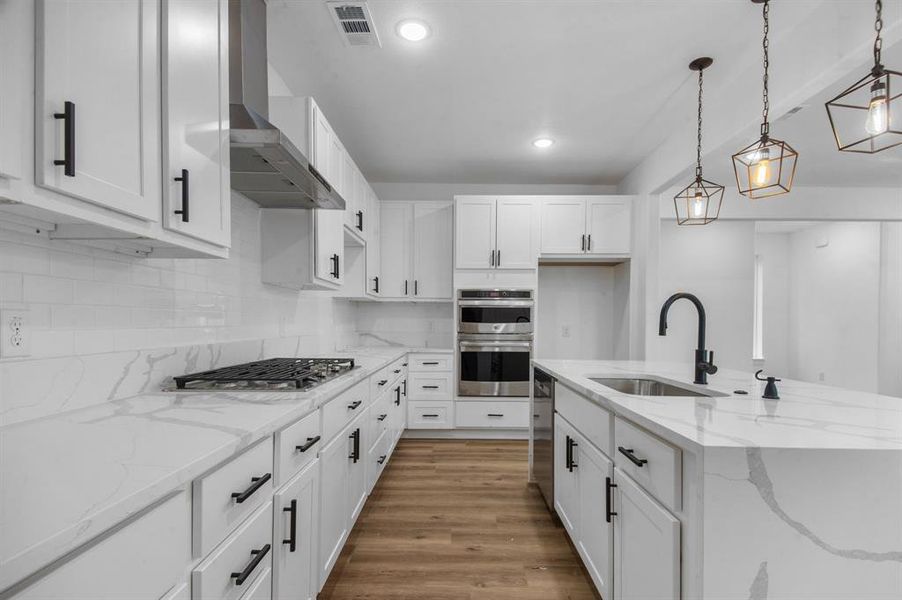 Kitchen with sink, white cabinets, hanging light fixtures, and stainless steel appliances