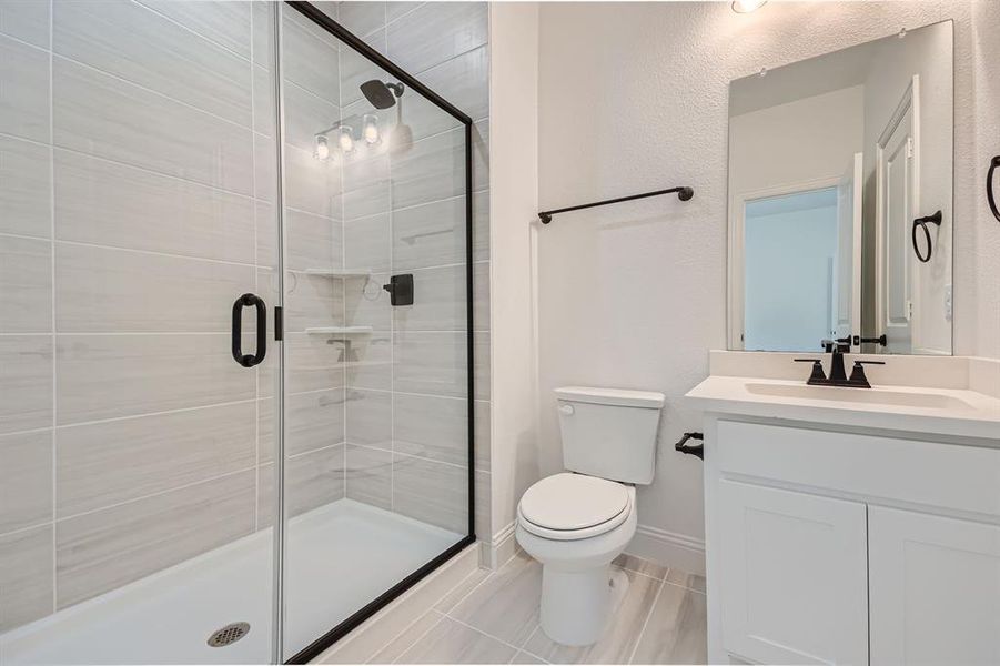 Bathroom featuring vanity, toilet, and a shower with door