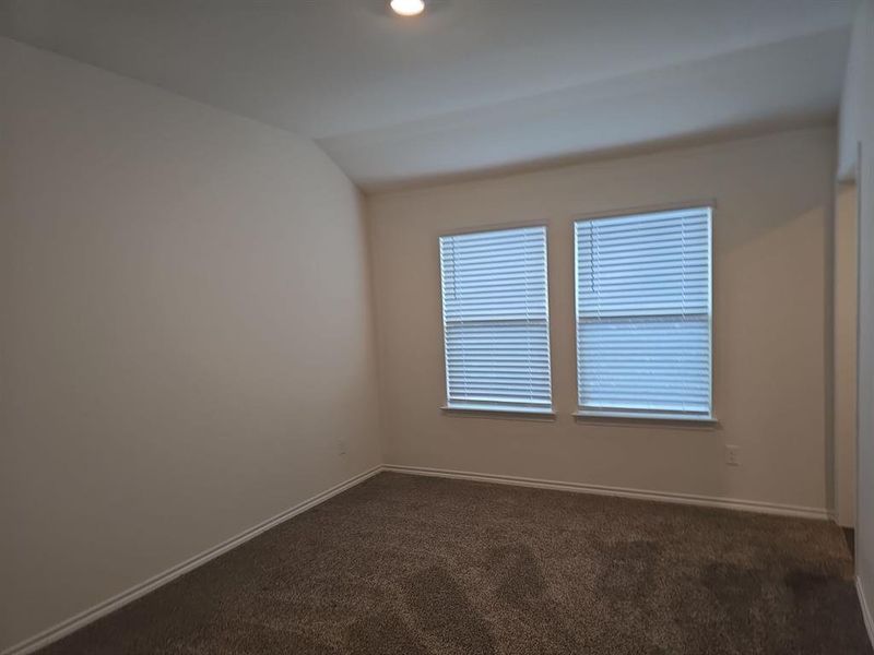 Unfurnished room with dark colored carpet and vaulted ceiling