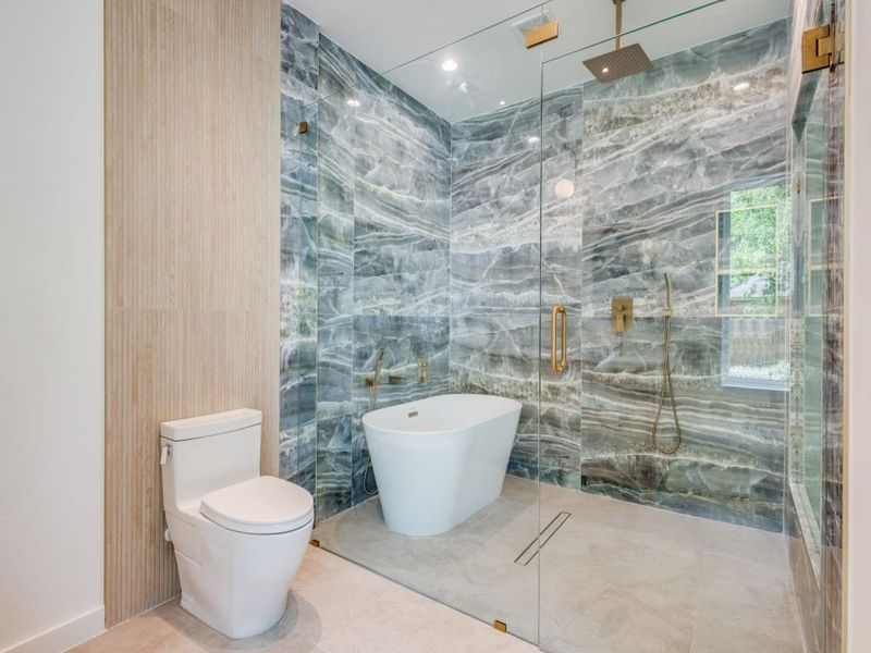 Bathroom featuring separate shower and tub, tile walls, and toilet