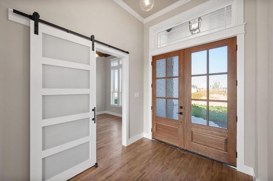 Doorway to outside featuring a wealth of natural light, french doors, a barn door, and wood-type flooring