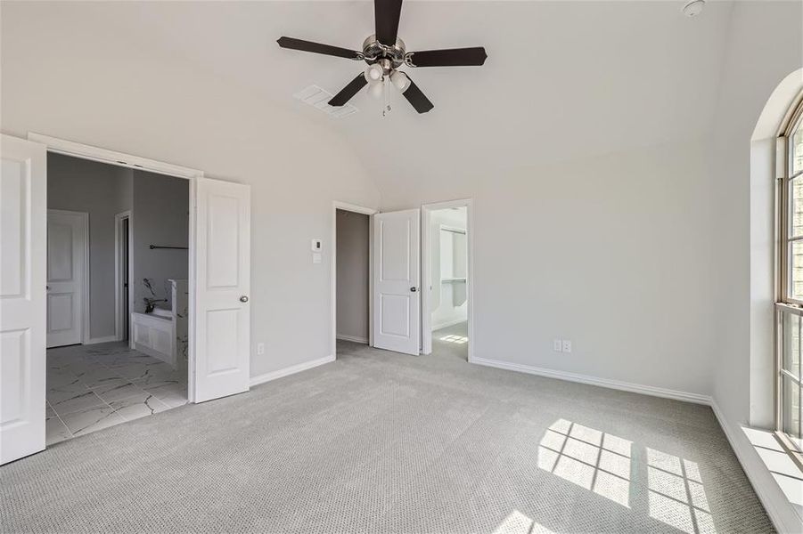 Unfurnished bedroom featuring ensuite bath, ceiling fan, lofted ceiling, and light colored carpet