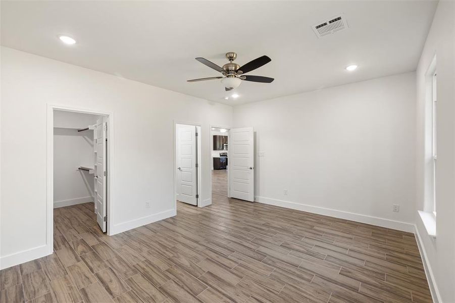 Unfurnished bedroom featuring a closet, light hardwood / wood-style floors, a walk in closet, and ceiling fan