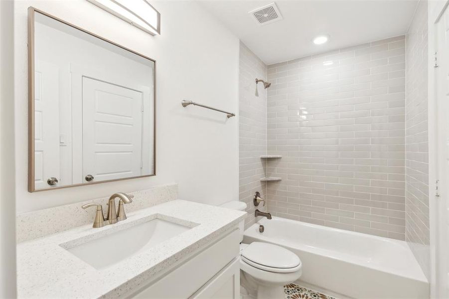 Full bathroom featuring tile flooring, toilet, vanity, and tiled shower / bath