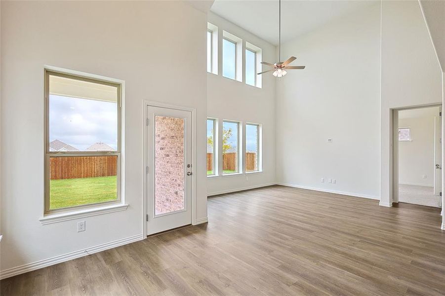 Spare room featuring light hardwood / wood-style flooring, ceiling fan, and a towering ceiling