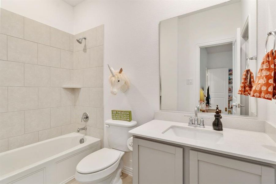 Full bathroom featuring vanity, tiled shower / bath combo, and toilet