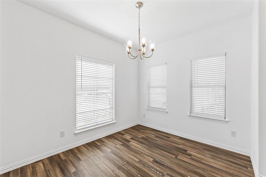 Unfurnished room with dark hardwood / wood-style flooring and a notable chandelier