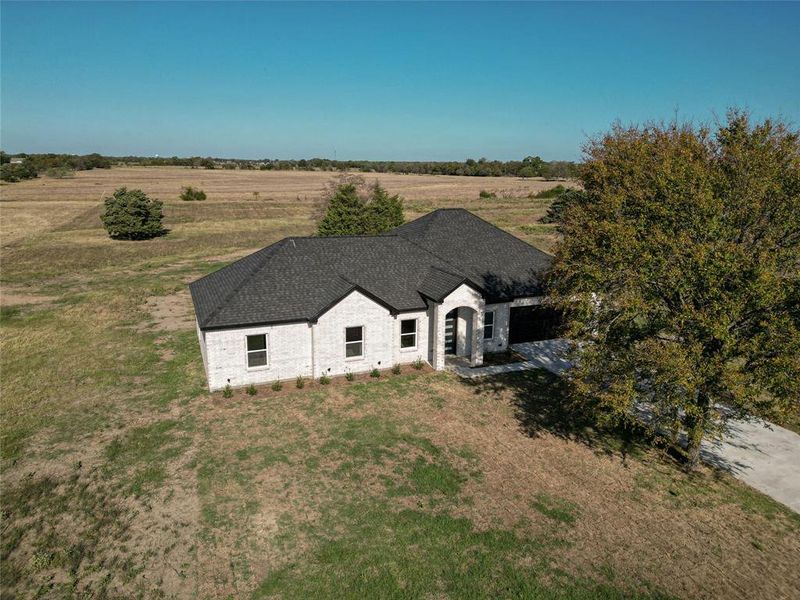 View of front of home with a rural view and a front lawn