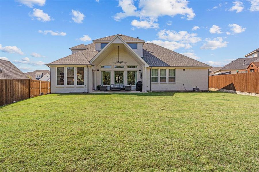 Back of property featuring a patio, a lawn, and an outdoor hangout area