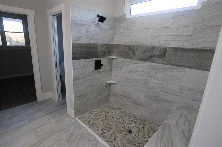 Bathroom with toilet, tile floors, and a tile shower