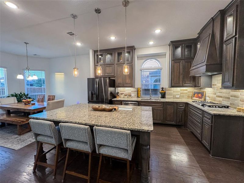 Kitchen featuring a center island, stainless steel appliances, dark brown cabinets, and dark hardwood / wood-style flooring