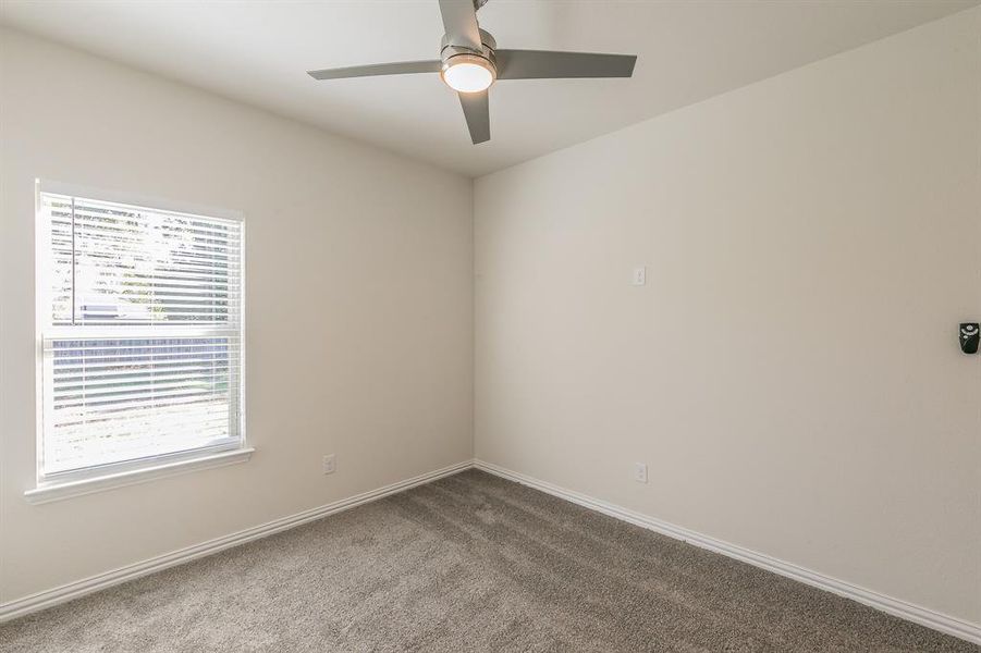 Carpeted spare room featuring ceiling fan