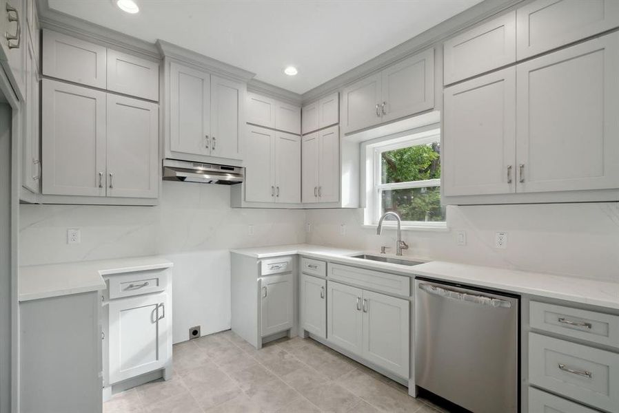 Kitchen with gray cabinetry, exhaust hood, sink, and stainless steel dishwasher