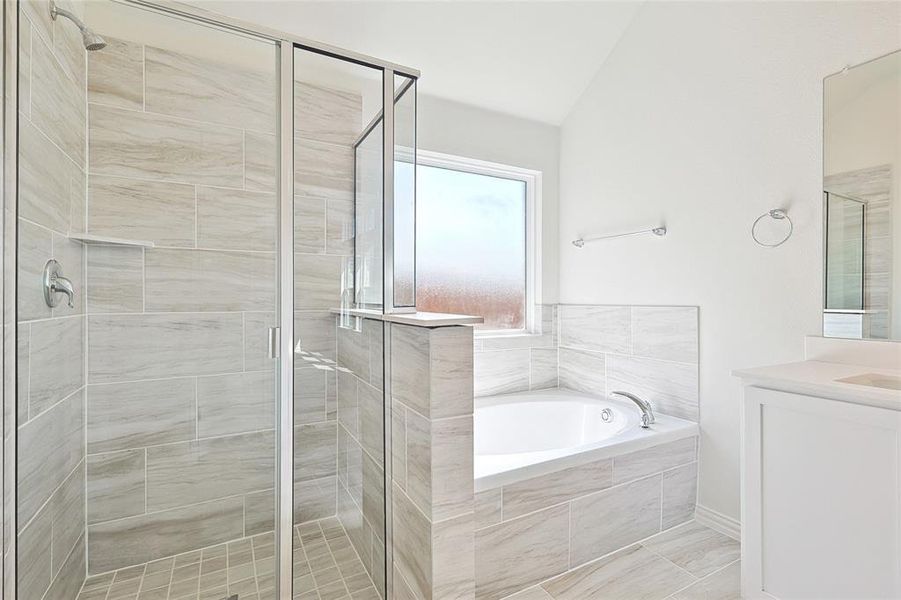 Bathroom featuring lofted ceiling, vanity, and plus walk in shower