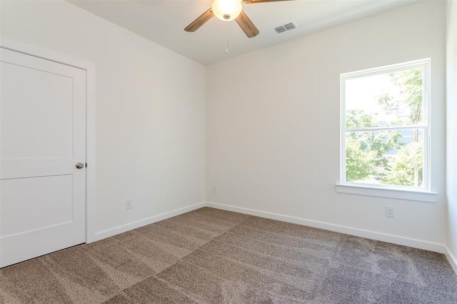 Carpeted empty room with plenty of natural light and ceiling fan