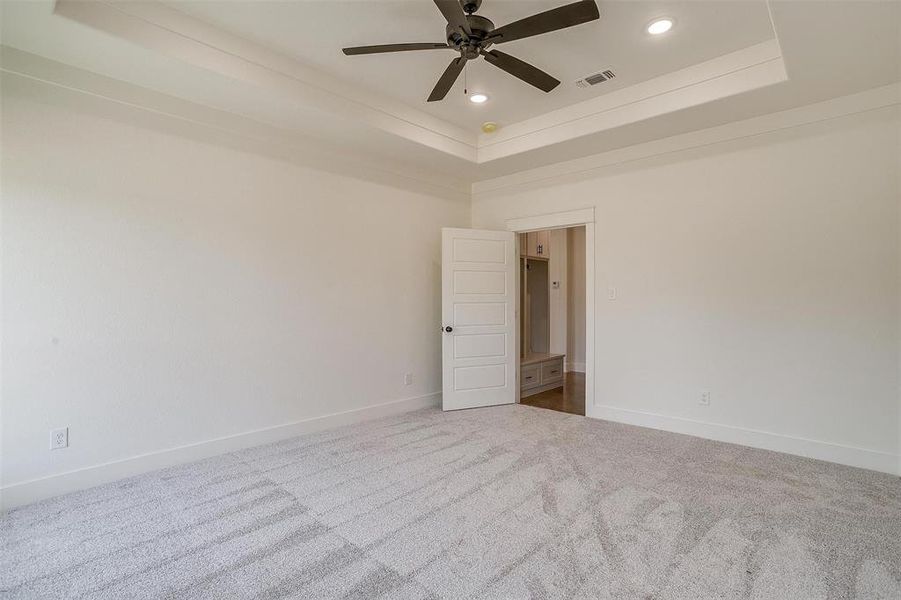 Carpeted empty room featuring a tray ceiling and ceiling fan