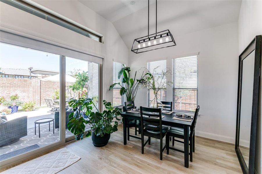 Dining room with vaulted ceiling, a beautiful chandelier, and light wood-type flooring