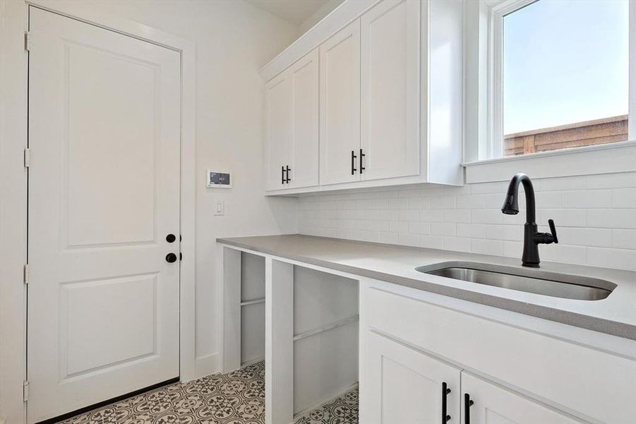 Laundry area featuring sink and light tile floors