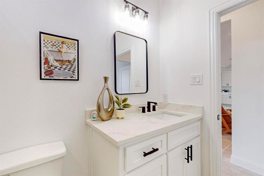 Bathroom with hardwood / wood-style flooring, vanity, and toilet