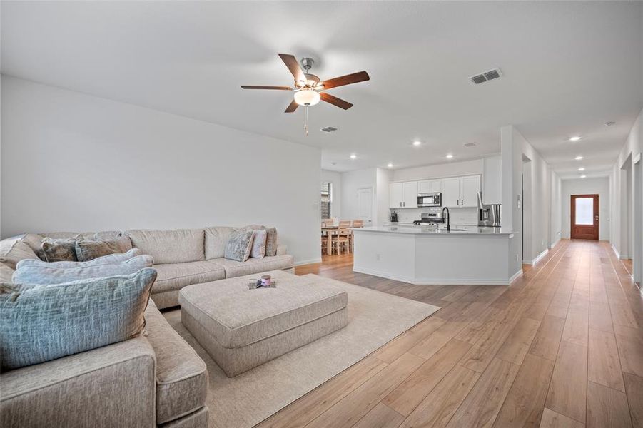 Living room with ceiling fan, sink, and light wood-type flooring