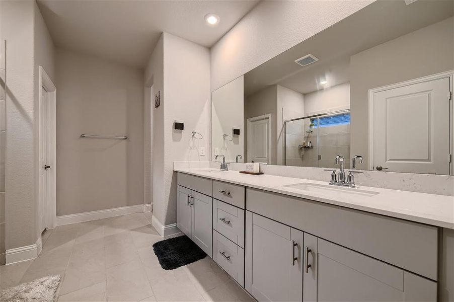 Bathroom with a shower, dual vanity, and tile floors