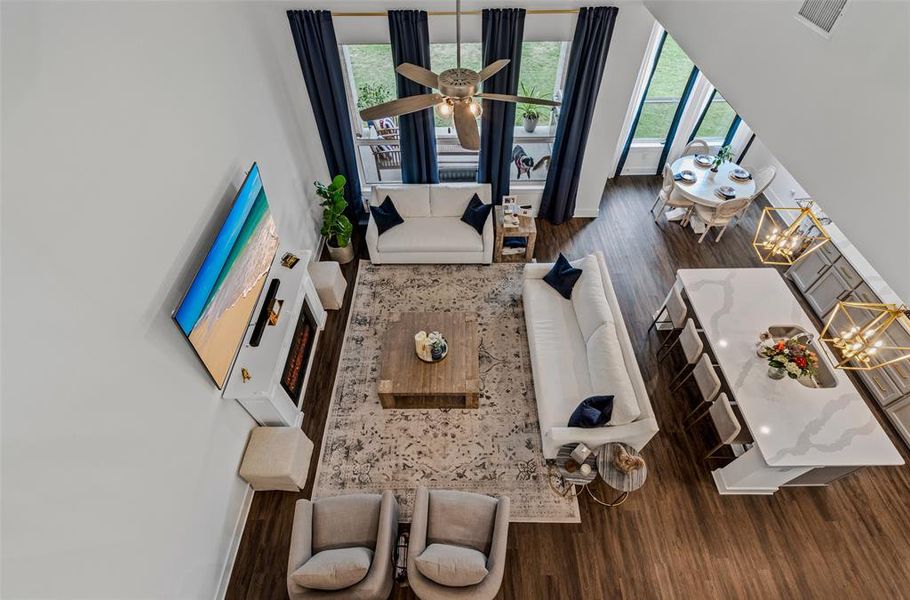 Living room with dark hardwood / wood-style floors, ceiling fan with notable chandelier, and plenty of natural light