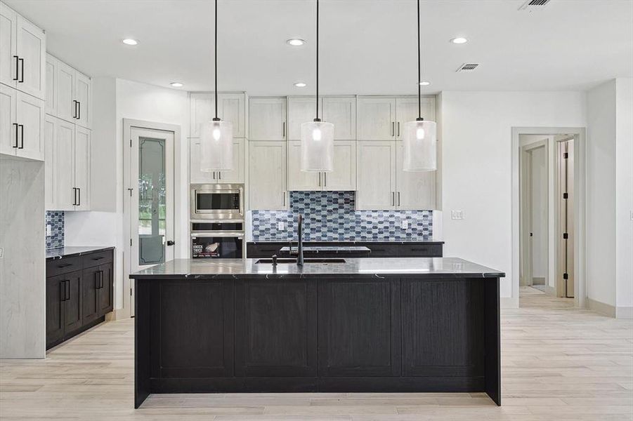 Kitchen with a kitchen island with sink, appliances with stainless steel finishes, white cabinets, and light hardwood / wood-style floors