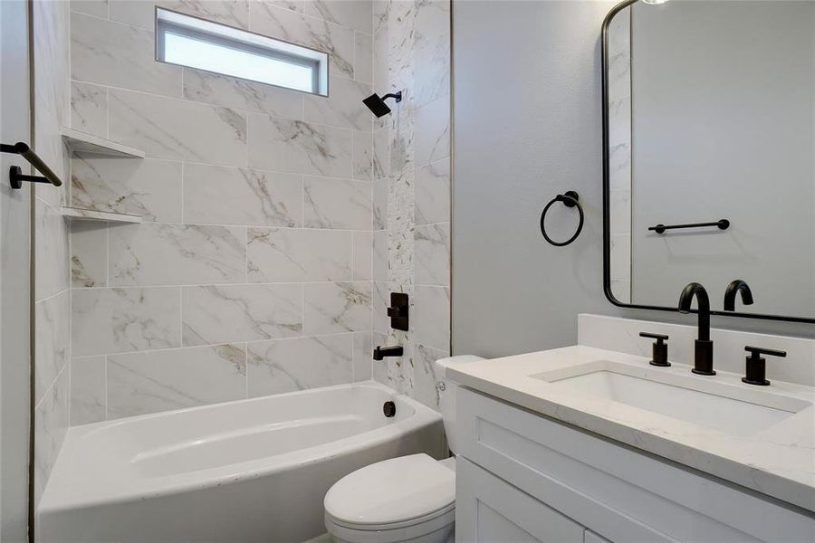 Full bathroom with tiled shower / bath combo, vanity, and toilet