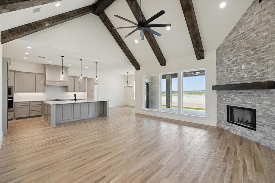 Unfurnished living room with high vaulted ceiling, a fireplace, light wood-type flooring, ceiling fan, and sink