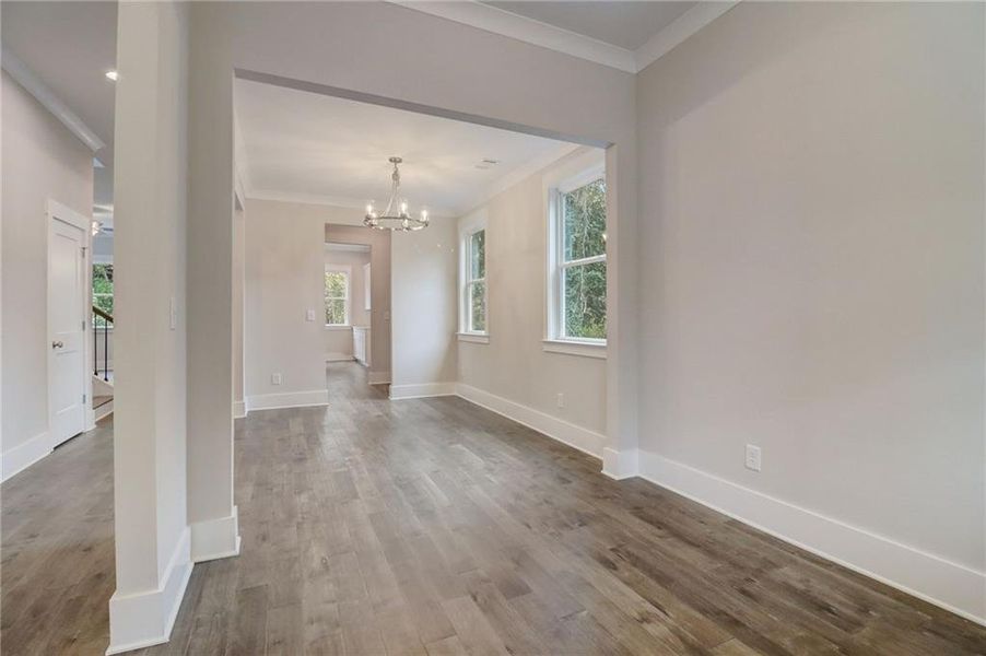 Entryway with ornamental molding, an inviting chandelier, a wealth of natural light, and hardwood / wood-style flooring