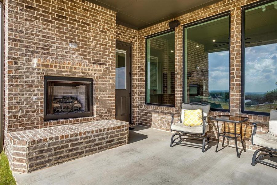 View of patio with an outdoor brick fireplace