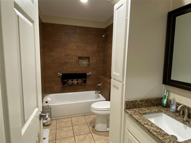 Full 2nd bathroom featuring tile flooring, toilet, vanity, and tiled shower / bath