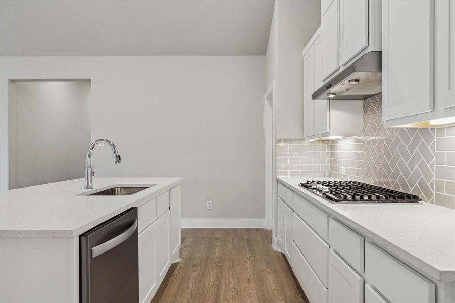 Kitchen featuring stainless steel appliances, white cabinets, hardwood / wood-style flooring, sink, and tasteful backsplash