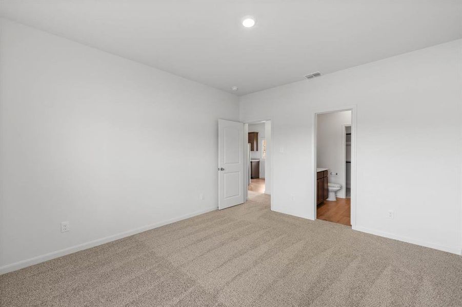 Bedroom featuring connected bathroom and light carpet