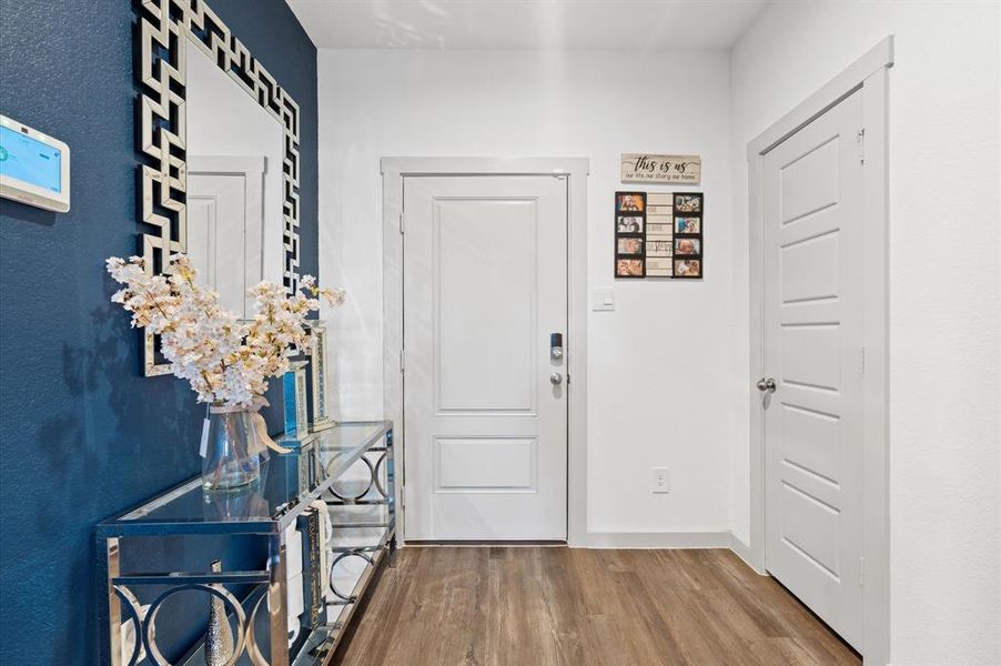 This is a modern and inviting well-lit entryway featuring a bold blue accent wall, and beautiful premium laminate flooring.