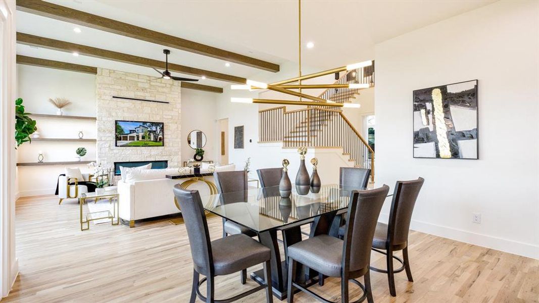 Dining room featuring a stone fireplace, beamed ceiling, and light hardwood / wood-style floors